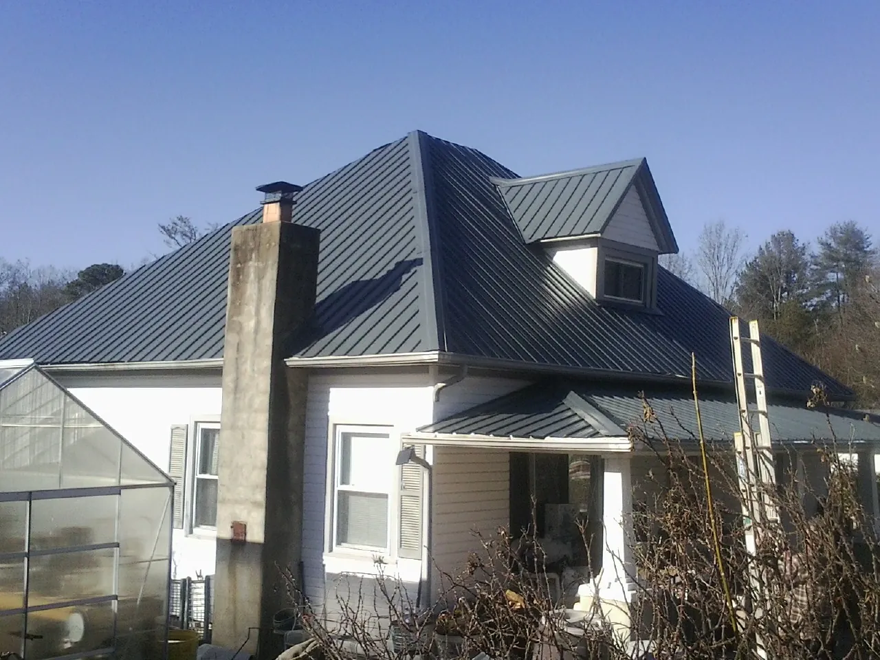 Dark blue standing seam metal roof on a white farmhouse with dormer — Slate & Tile Roof Repair by Roofing Brothers in Temperanceville