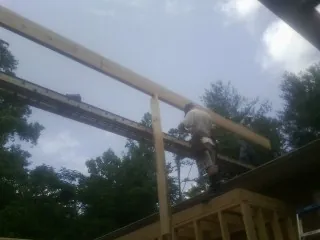 Carpenter setting a ridge beam over a new addition frame — Ice Dam Removal by Roofing Brothers in Temperanceville