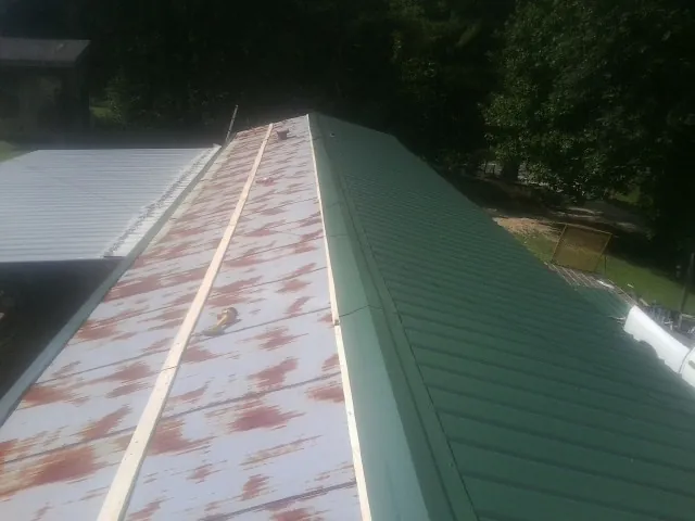 Old rusted panels beside newly installed green metal roofing — Wind Damage Roof Repair by Roofing Brothers in Temperanceville