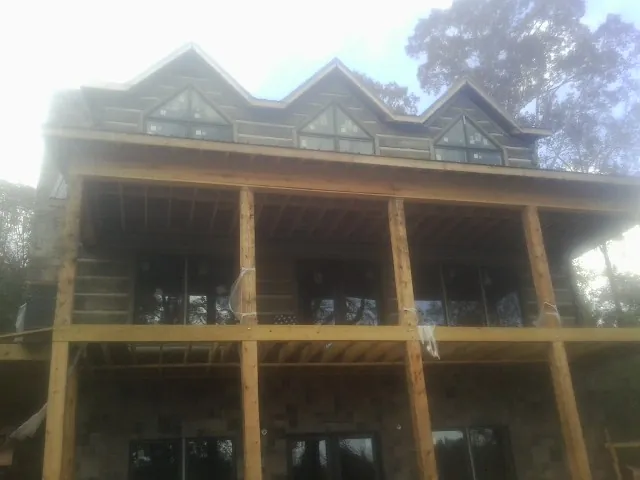 Dormers and porch framing on a large log home under construction — Roof Coating work by our crew in Temperanceville