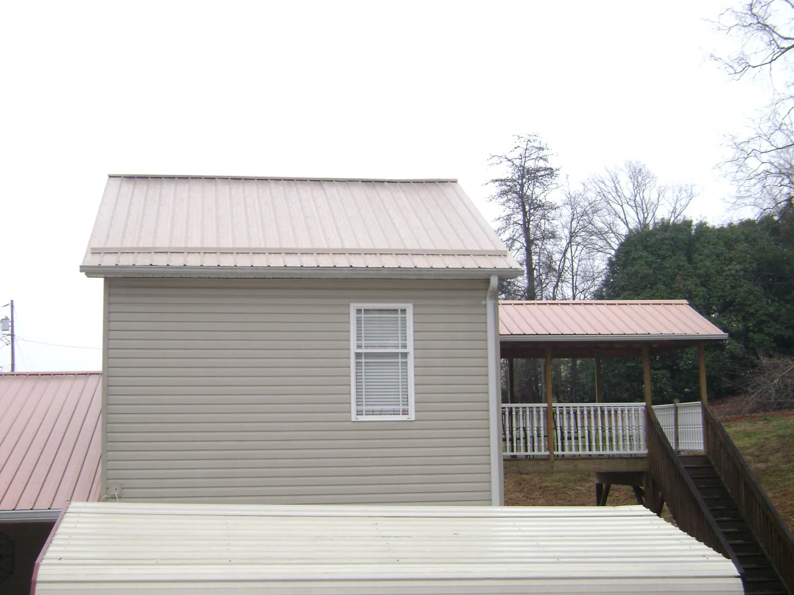 Tan metal roofs on a two story addition and attached porch, from a Roof Replacement job in Temperanceville