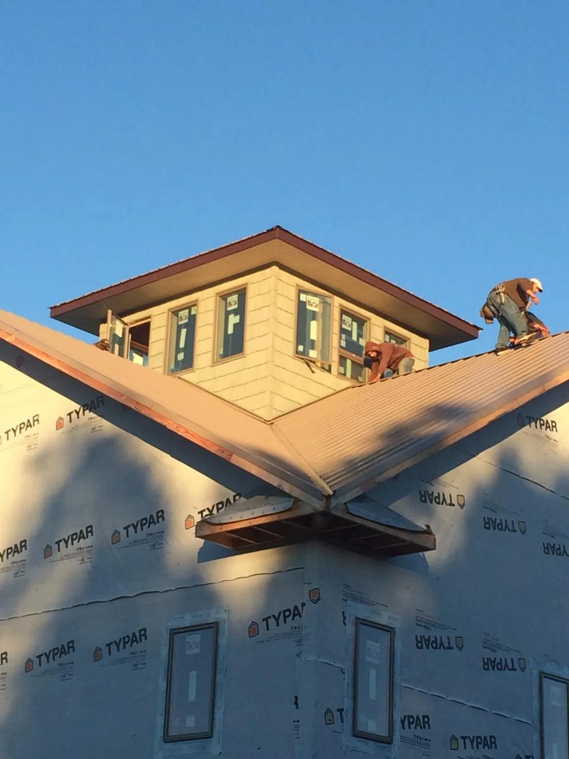 Roofers working around a rooftop cupola on a new metal roof at sunset — Roof Waterproofing in Temperanceville by Roofing Brothers